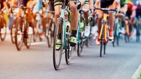 A peloton of male bike riders race on a road
