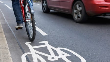 woman cycling past car driving on road