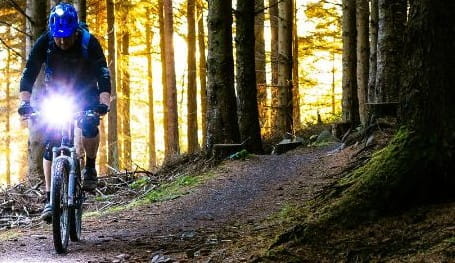 A man riding a mountain bike through a forest at night